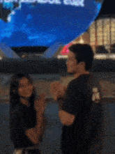 a man and a woman are clapping their hands in front of a large screen that says u.s. aquarium