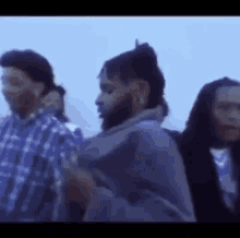 a group of men are standing next to each other in a line and one of them has a beard .