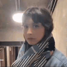 a young girl is wearing a scarf around her neck and a denim jacket .