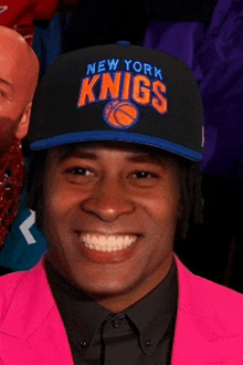 a man wearing a new york knicks hat and a pink jacket