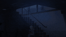 a person sitting on a chair in a dark room next to a staircase
