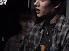 a man wearing a plaid shirt is talking to another man