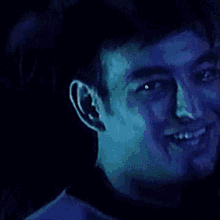 a close up of a man 's face with a blue light behind him