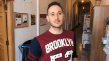 a man wearing a brooklyn got money t-shirt stands in a hallway