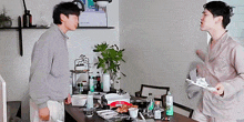 two men are standing in front of a table with a tray of food on it ..