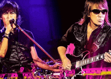 a man is singing into a microphone while another man plays a guitar