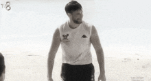 a man in a kappa shirt is standing on the beach