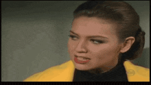 a close up of a woman wearing a yellow jacket and a black turtleneck
