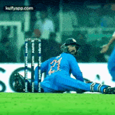 a cricket player is doing a split on the field during a game .