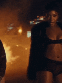 a woman in lingerie is standing next to a man in a fur coat .