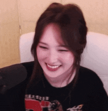 a woman is smiling while sitting in front of a microphone in a chair .