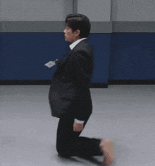 a man in a suit is kneeling on the floor holding a bag .