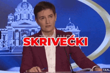a man in a red jacket stands in front of a microphone with the word srivecki written in red