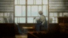 a man in a kimono is sitting in front of a window