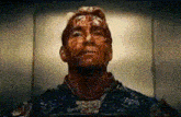 a man with blood on his face is looking up at the camera