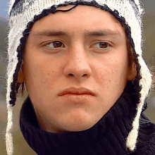 a close up of a man wearing a hat and a black turtleneck