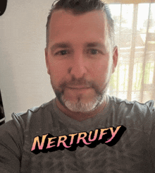 a man wearing a nertrufy shirt looks at the camera