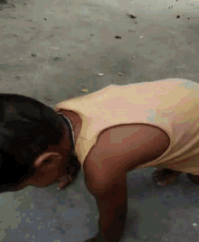 a young boy in a yellow tank top is doing push ups on the ground