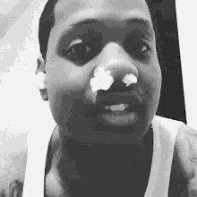 a black and white photo of a man with a tissue in his nose