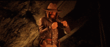 a man in a cowboy hat is standing in a dark cave