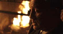 a close up of a man 's face with a fireplace in the background