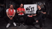three men are sitting in front of a sign that says hey ( ew )