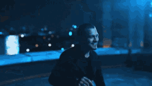a man is smiling in a dark room with a blurry background .