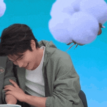 a man in a green jacket is sitting in front of a blue background