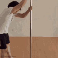a man is standing on a pole with his arms outstretched in a room .