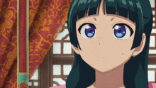 a girl with blue eyes is standing in front of a red curtain