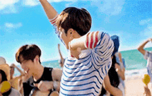 a man in a striped shirt is dancing on the beach .