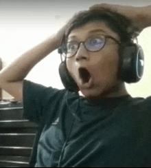 a young boy wearing headphones and glasses is making a funny face .