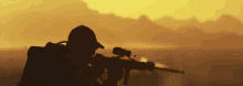 a silhouette of a soldier holding a rifle at sunset .