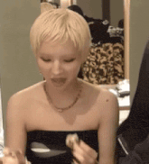 a woman with short blonde hair is wearing a black strapless top and a necklace
