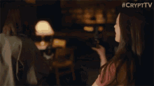 a woman is holding a glass of wine in her hand while another woman holds a bottle of wine .