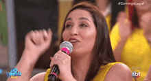 a woman singing into a microphone with the hashtag #domingolegal on the bottom