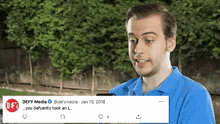 a man in a blue shirt is looking at a cell phone next to a defy media tweet