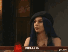 a woman with blue hair is sitting in front of a sign that says " omg focus "