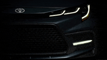 a close up of the front of a toyota car in the dark