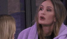 a woman wrapped in a purple blanket is making a funny face while looking up .