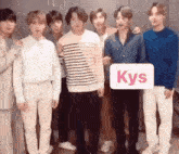 a group of young men are standing next to each other and holding a sign that says kys .