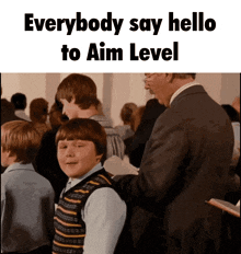 a man in a suit stands next to a boy in a striped vest and says everybody say hello