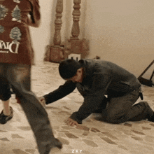 a man kneeling on the floor with the word zky written on the bottom
