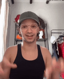 a man wearing glasses and a baseball cap is giving a thumbs up