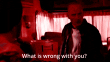 a man in a mask stands in a dark room with the words " what is wrong with you " above him