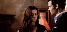 a man and a woman are standing next to each other in a living room .