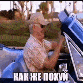 a man in a hat is driving a car with the hood up and a foreign language written on it .