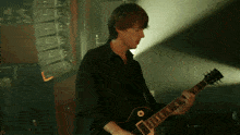 a man in a black shirt plays an electric guitar