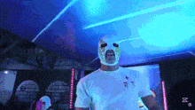 a man wearing a mask and a white shirt is standing in a dark room with blue lights .
