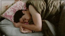 a man is sleeping in a bed with a pillow and blanket .